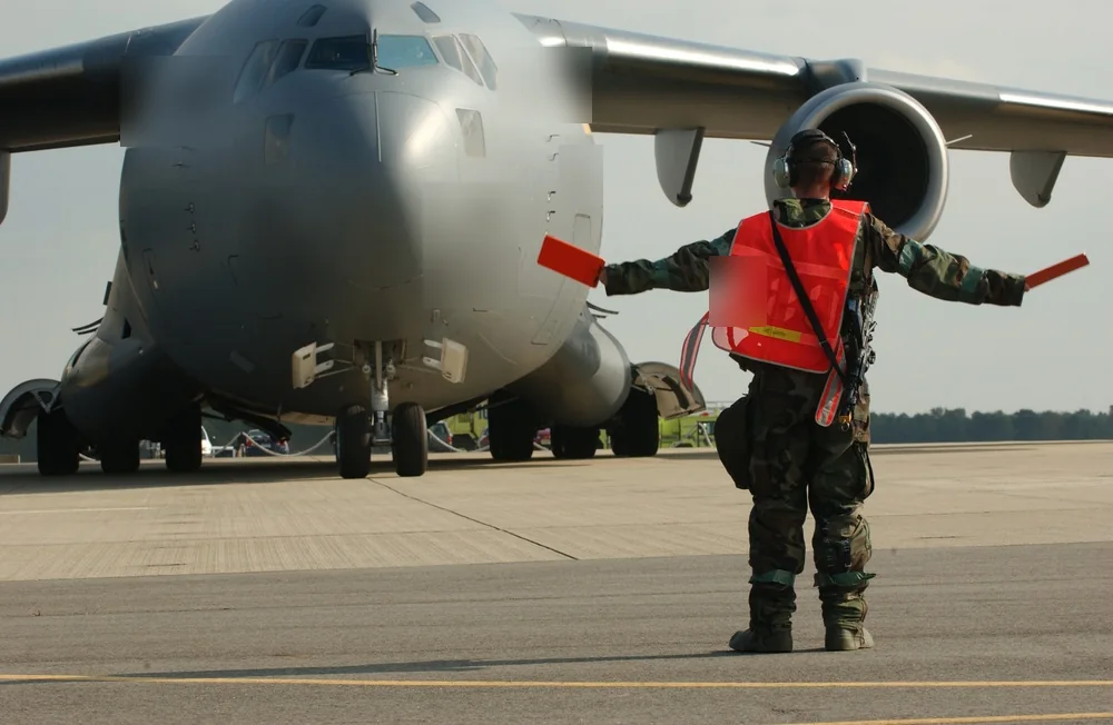 C-17 transport aircraft guided on an airfield by a ground crew member