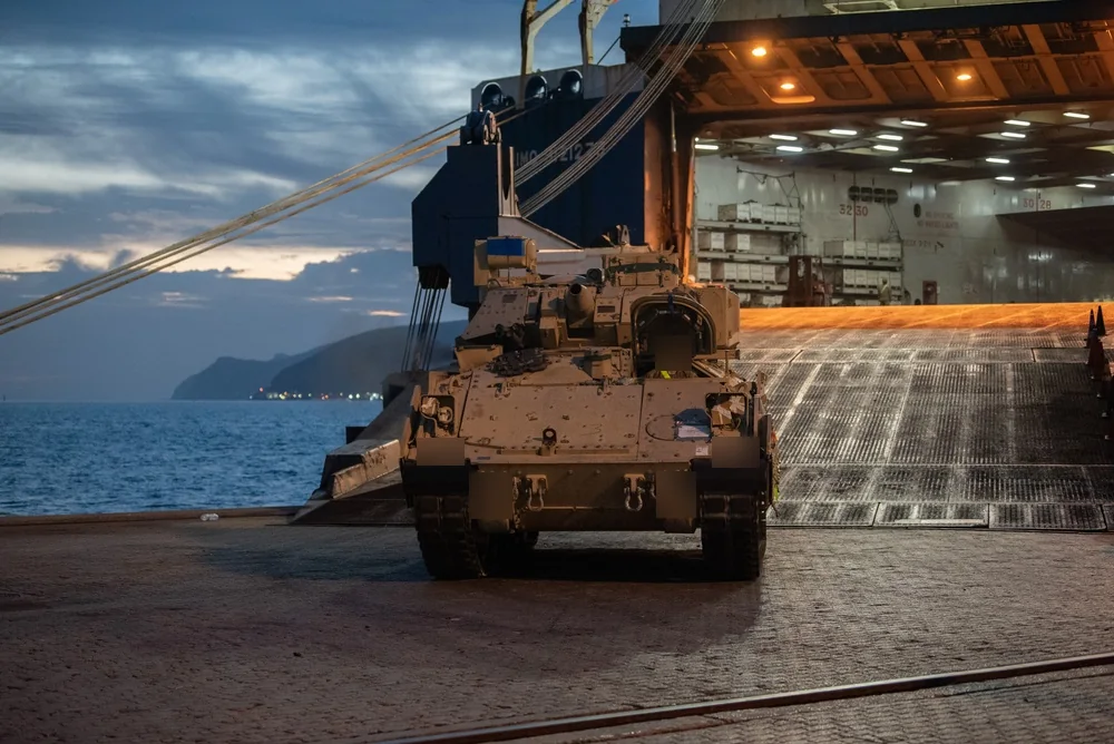 Bradley fighting vehicle at a cargo ship ramp during port logistics operations
