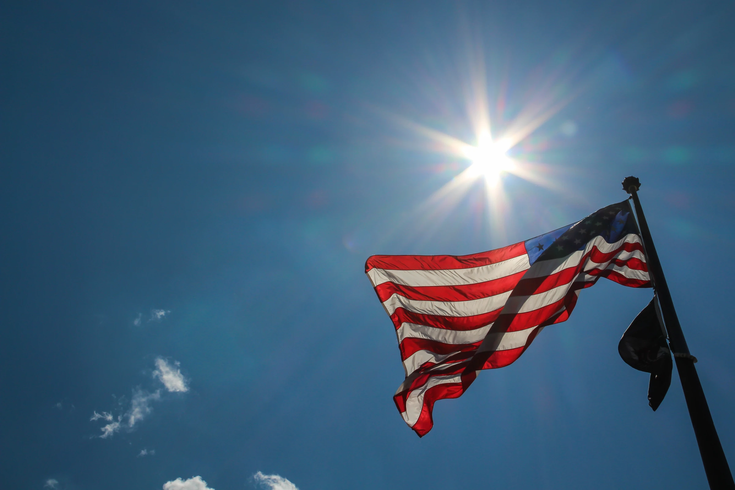 U.S. flag billowing in sunlight against a blue sky